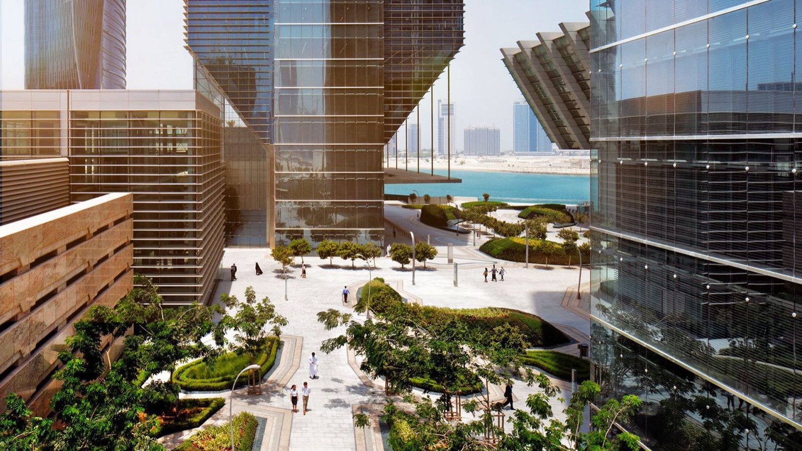 Towers and a landscaped plaza in a Gulf financial district, looking out to the water