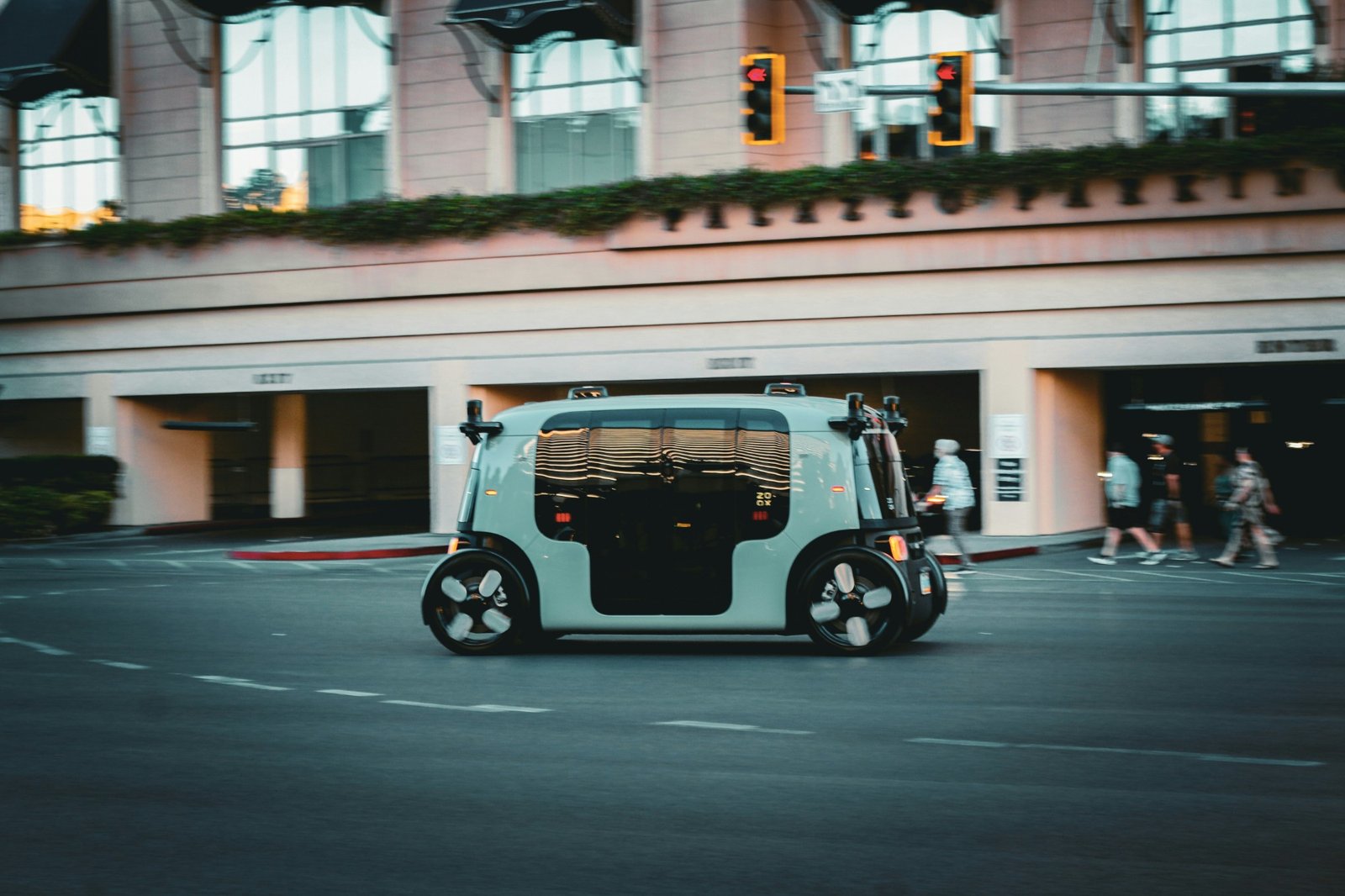 A driverless autonomous vehicle moving through a city street at dusk