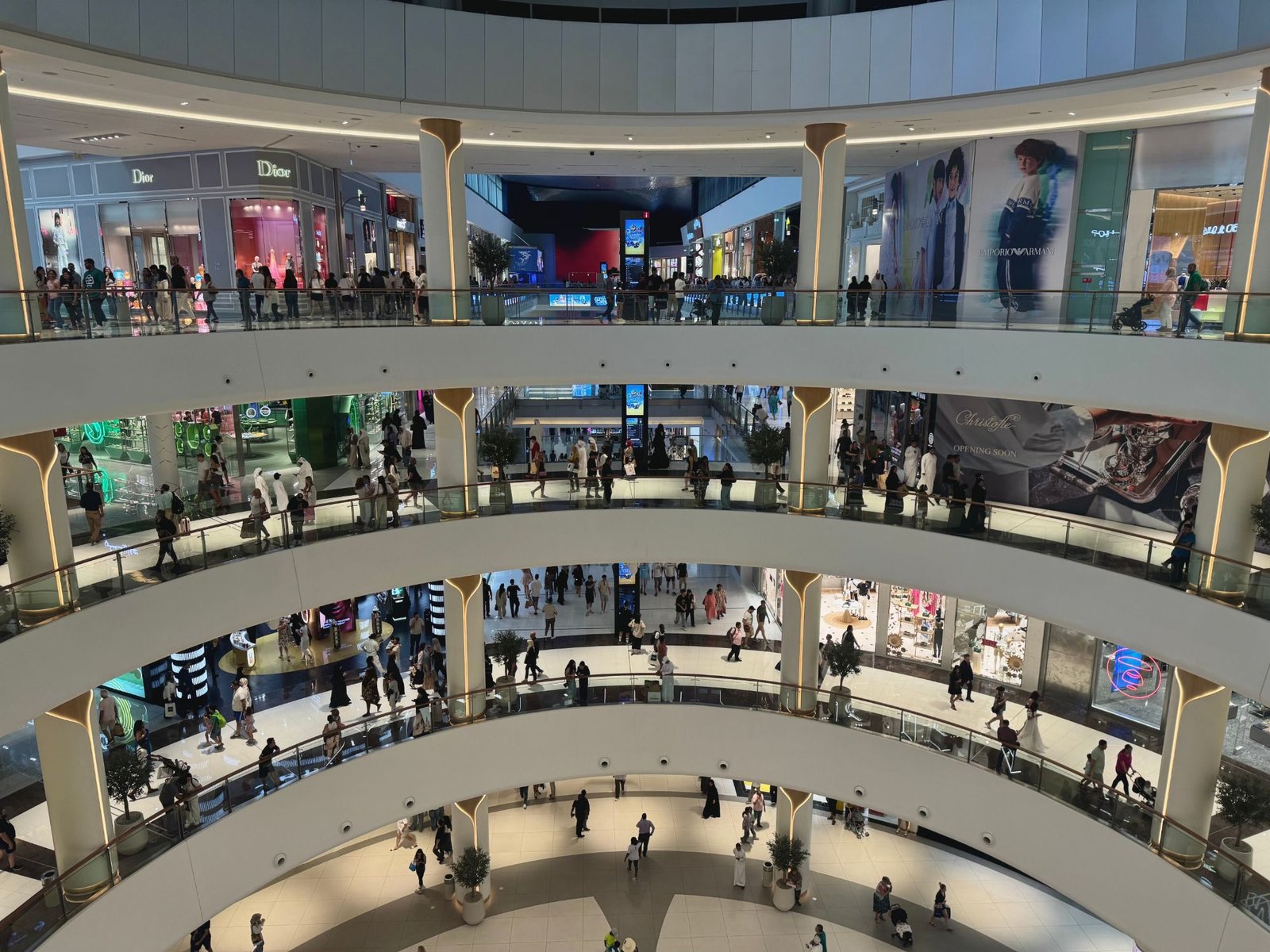 The atrium of a large Gulf shopping mall seen from an upper level, shoppers on four curved balconies